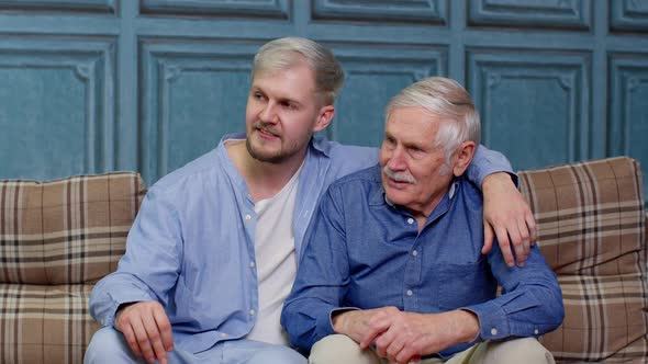Family of Senior Father and Adult Son or Grandson Having Conversation Chatting Relaxing on Couch