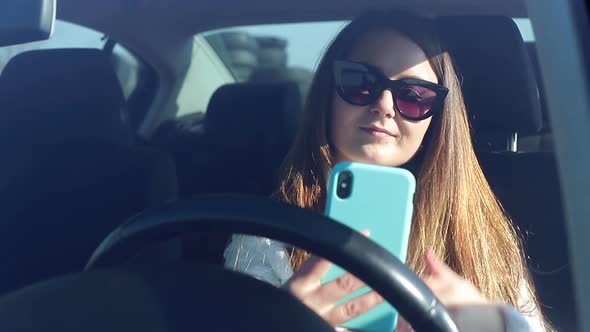 Girl Uses a Smartphone While Sitting in the Car