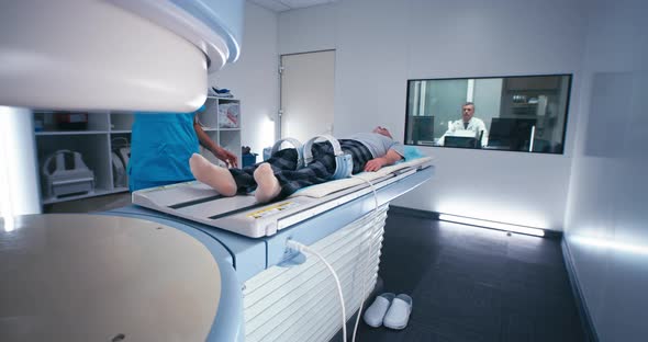 Diverse Doctors Starting MRI Procedure of Elderly Man