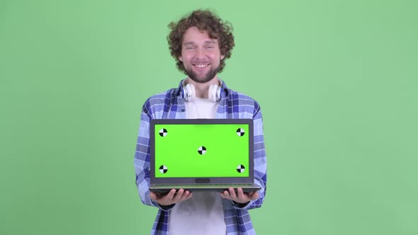 Happy Young Bearded Hipster Man Showing Laptop
