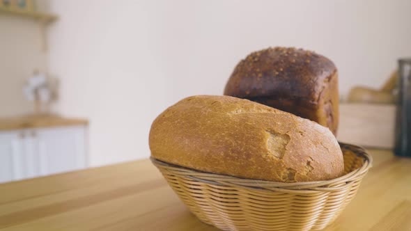 Woman Takes Basket with Homemade Bread From Table Closeup