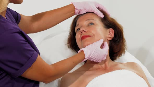Aged Woman Smiling While Cosmetologist Examining Her Face