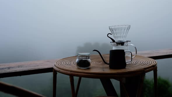 A set of drip coffee equipment on wooden table at the terrace on foggy day