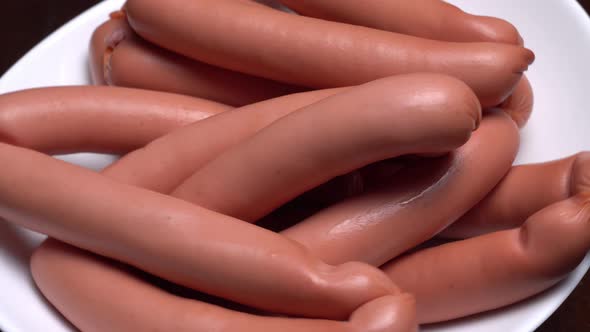 Sausages spinning on a white plate on a black background.