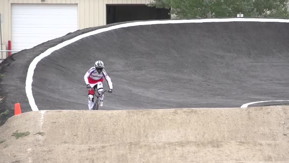 A young man bmx rider riding on a dirt track.