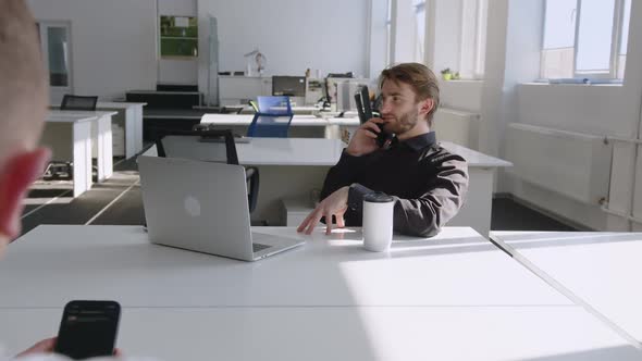 Man Talks on His Phone and Looks on the Clock