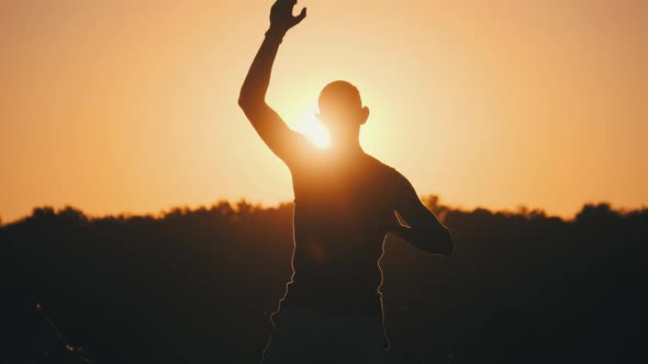 Silhouette of Man Against Sunset Raising Hands Up. Freedom. Slow Motion