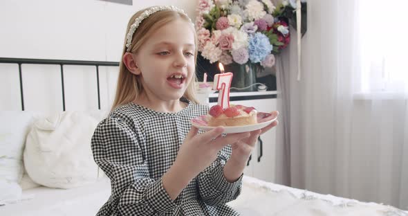 A Birthday Party for a Happy Cute 7 Year Old Girl and Blowing Candles on a Cake