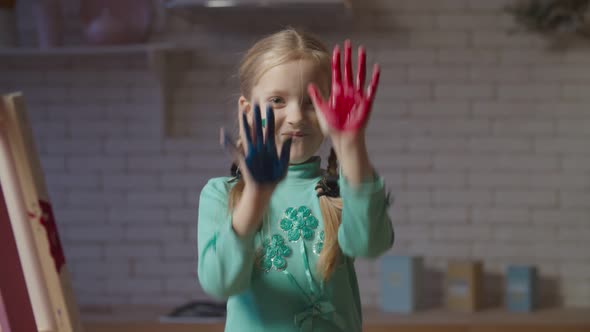 Cute Little Girl with Hands in Colorful Paints