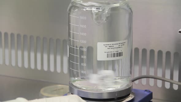 Medicine in glass jar being mixed by a magnetic mixer.