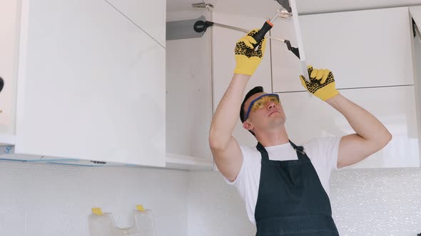 Installation of Furniture handles on a white cabinet. Master with screwdriver.