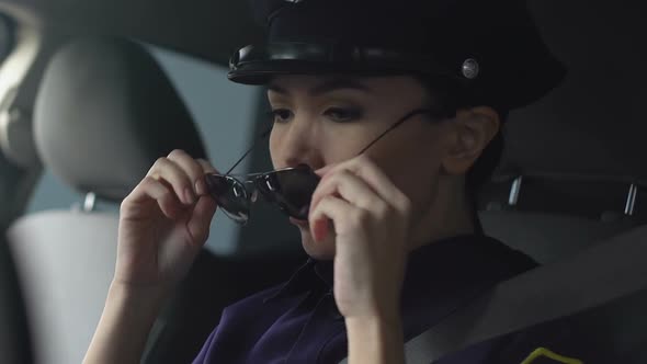 Asian Lady Police Officer Rubbing Nasal Bridge and Taking Off Hat After Hard Day