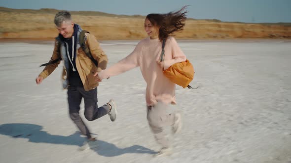 Happy Lovely Couple Millenial Hipsters Walking Hand To Hand and Joyfully Running on Pink White Salty