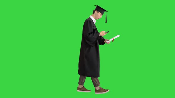 Graduation: Happy Student Walking and Texting on His Phone on a Green Screen, Chroma Key