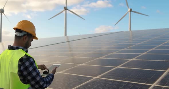 Young man working with digital tablet inside wind farm - Ecology concept
