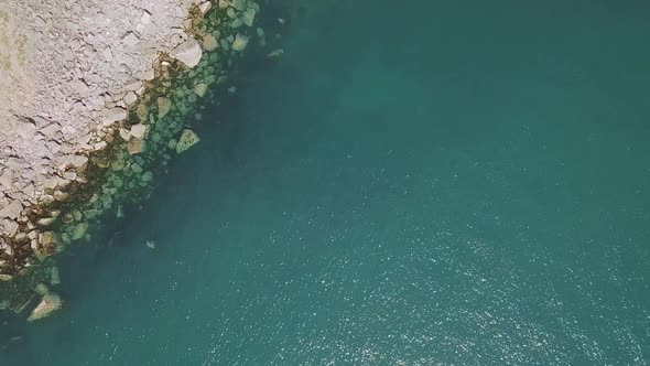 Aerial Top Down shot of beautiful water, revealing a Bay and Cliffside.