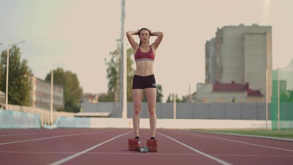 Caucasian Young Brunette Woman Shit for a Run in the Stadium Comes Up to the Running Sides and