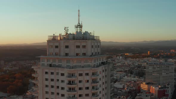 Orbit Shot Around Top of Torre De Madrid Historic Tall Skyscraper at Sunset