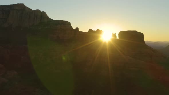 The morning sun silhouettes Bear Mountain and surrounding rock formations near Sedona, Arizona at da