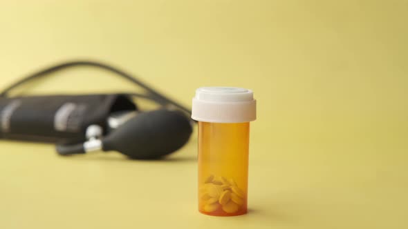 Orange and White Medical Pill Container and Blood Pressure Machine on Table 