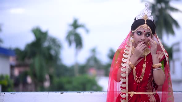 An Indian Bride is wearing a nose ring outdoor on cloudy evening