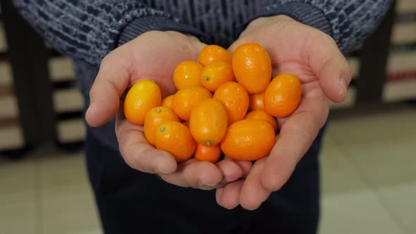 Closeup of a Man Holding a Kumquat in a Grocery Store