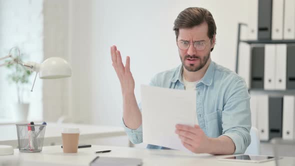 Young Man Reacting To Loss Documents