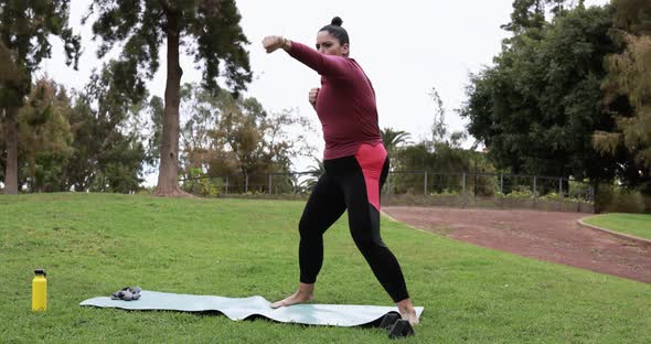 Curvy woman doing boxing exercises at park - Sport and workout concept