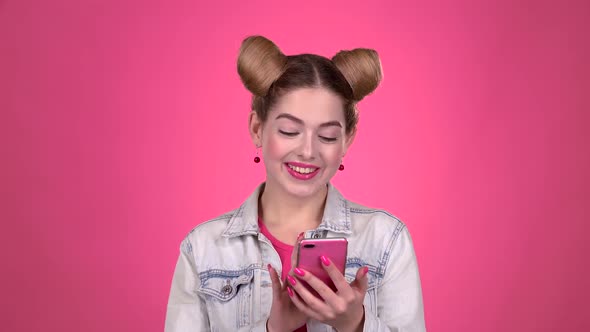 Teenager Thumbs a Photo on a Smartphone. Pink Background. Slow Motion