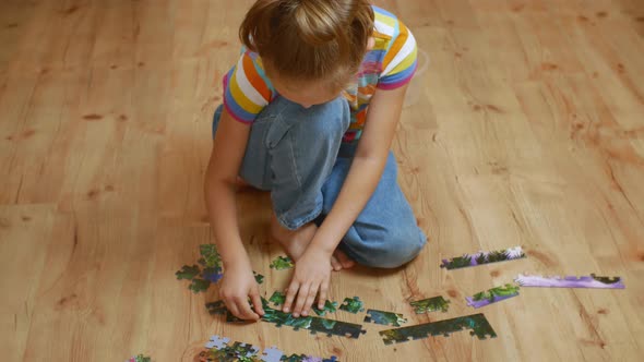 Closeup of a Playing Child Sitting on the Floor and Collecting Puzzles