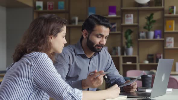 Indian Teacher or Mentor Helping Latin Student Teaching Intern Using Laptop