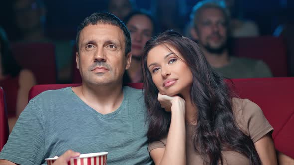 Happy Couple Watching Romantic Movie at Cinema Hugging Enjoying Date Surrounded By Crowd Spectators