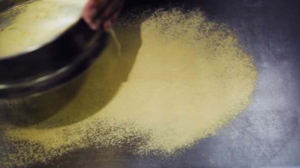 Italian chef sift flour through screen in restaurant kitchen