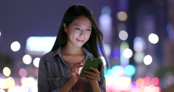 Woman using cellphone in city of Taipei at night