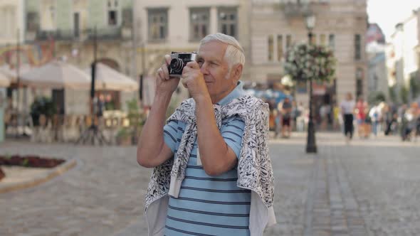 Senior Male Tourist Exploring Town and Makes a Photo with Retro Photo Camera