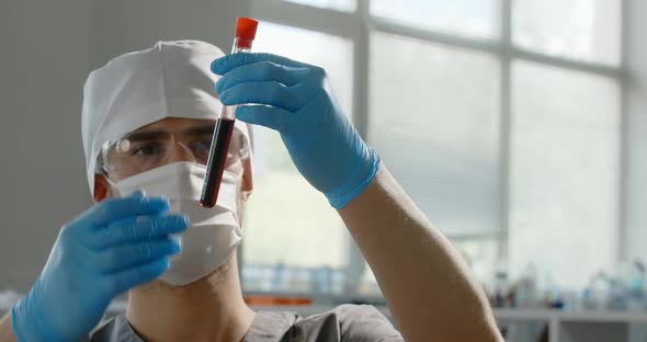 Medic in Mask Checks Test Tube with Blood in Laboratory