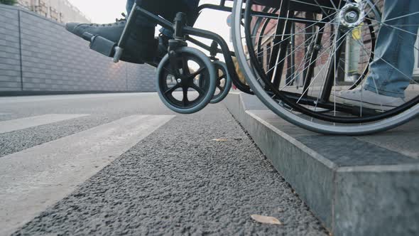 Closeup Wheelchair Wheel Gently Slowly Descending From Curb of Sidewalk Into Pedestrian Crossing