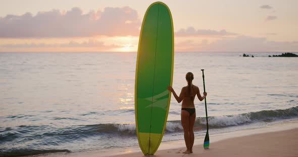 Young woman enjoying sunset on the beach with stand up paddle board