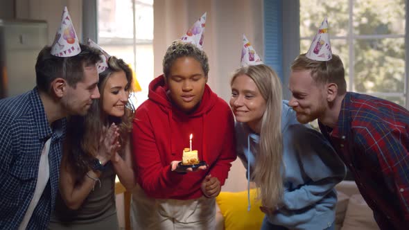 African Woman Celebrating Birthday with Friends Blowing Out Candle on Cake