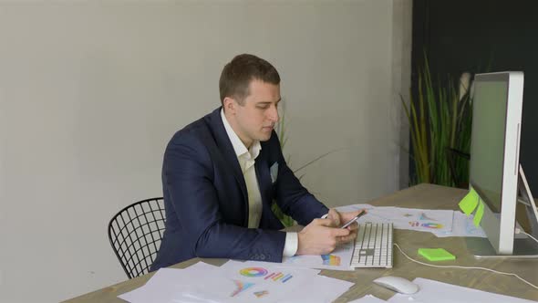 a man in a business suit with a smartphone sits in the office