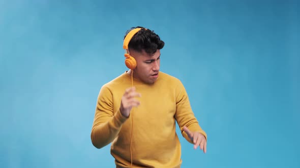 Man enjoying listening to music with headphones while standing on an isolated background.