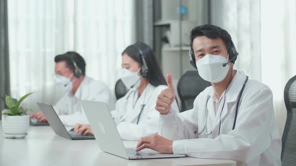 A Man Of Three Asian Doctors In Mask Working As Call Centre Agent Looking at camera And Thumbs Up