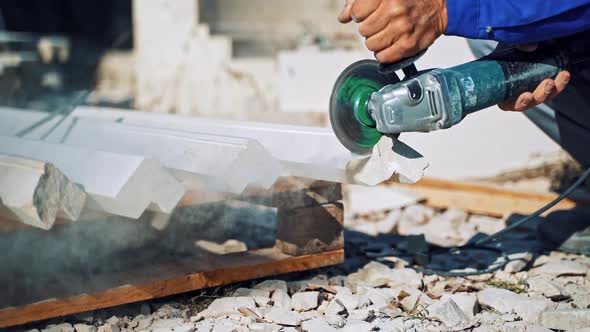 Worker cutting stone block. Worker with a small angle grinder cuts a granite