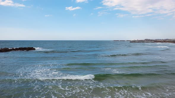 Mediterranean Sea and blue sky with gentle surf flying out to reveal young attractive romantic coupl