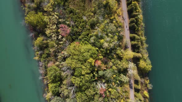 Aerial view of cyclists biking along the river. A group of cyclists on a forest dirt path by the wat