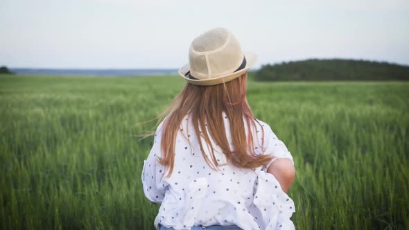 Pretty Child in the Hat Is Running Across the Wheat Field