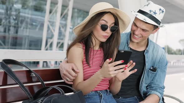Traveling. Couple Using Phone, Waiting Transport Near Airport