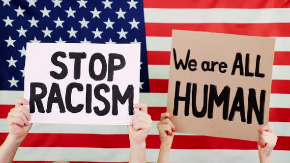 Protesters Hold Banners with Slogans - Stop Racism. We Are ALL HUMAN - Against Background of the USA