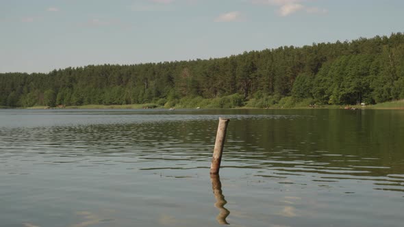 Reflections Through Calm Water Of Jezioro Glebokie Lake During Daytime In Poland. Pan Left Shot