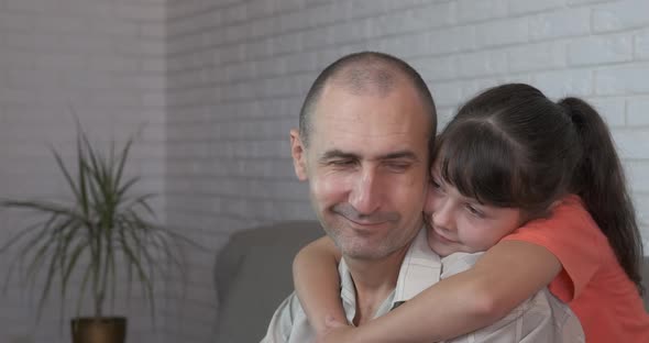 Child embrace dad on sofa. 